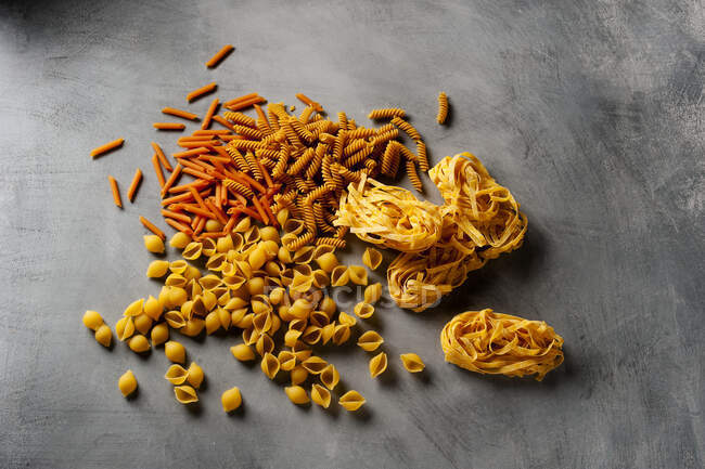 Raw pasta selection on grey background — Stock Photo