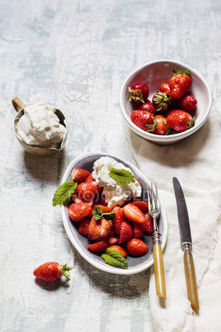 Whipped cream in jug with fresh strawberries in bowls — Stock Photo