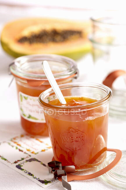 Homemade papaya jam in glass jars and fruit on background — Stock Photo