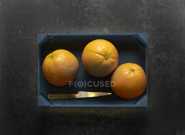 Three oranges in a wooden crate — Stock Photo