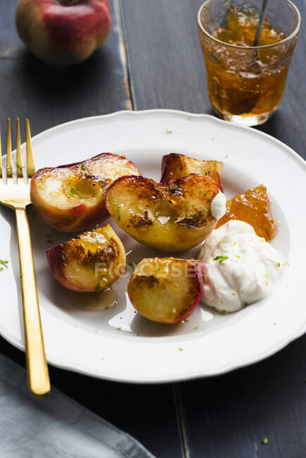 Grilled peaches with cream, orange marmalade and lime zest — Stock Photo