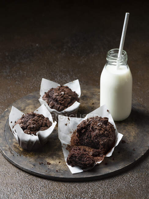 Chocolate muffins with milk on brown background — Stock Photo