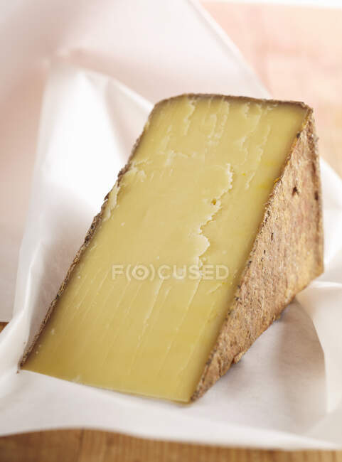 Mountain cheese piece in paper wrap — Stock Photo