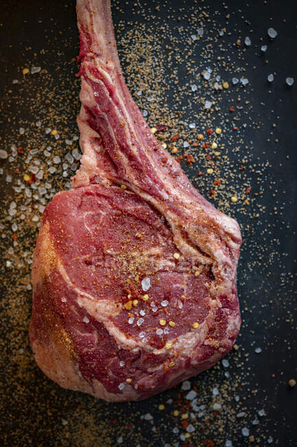 Tomahawk steak with spices on black background — Stock Photo
