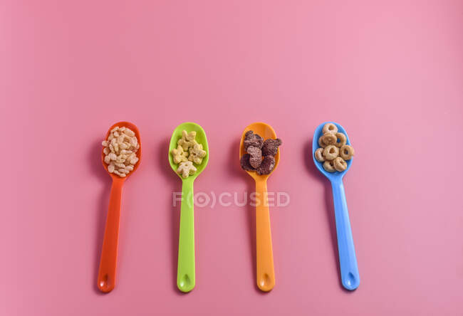 Varios cereales para el desayuno en cucharas de plástico - foto de stock