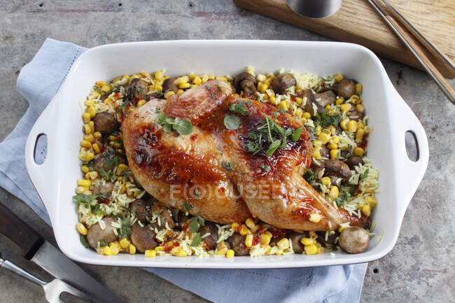 Meio frango assado em um prato com arroz, milho e cogumelos — Fotografia de Stock