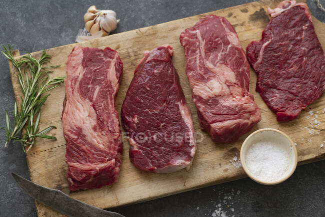 Various raw Black Angus steaks on a wooden board — Stock Photo