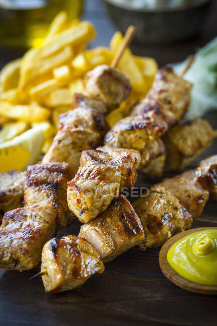 Souvlaki griego servido con papas fritas y salsa de mostaza - foto de stock