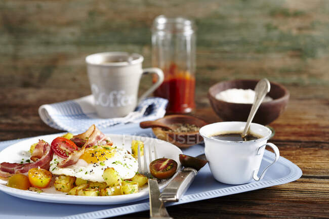 Gebratene Kartoffeln, Speck, Spiegelei und Tomaten und Frühstück mit Kaffee — Stockfoto