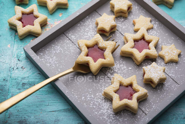 Estrellas de pastelería llenas de mermelada de fresa en bandeja de madera y mesa - foto de stock