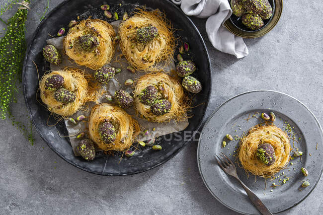 Easter eggs coated in dates, cocoa and pistachios in angel hair pasta nests — Stock Photo