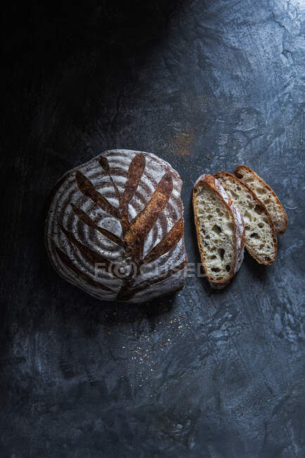 Источниковый хлеб и ломтики хлеба на деревенской поверхности — стоковое фото