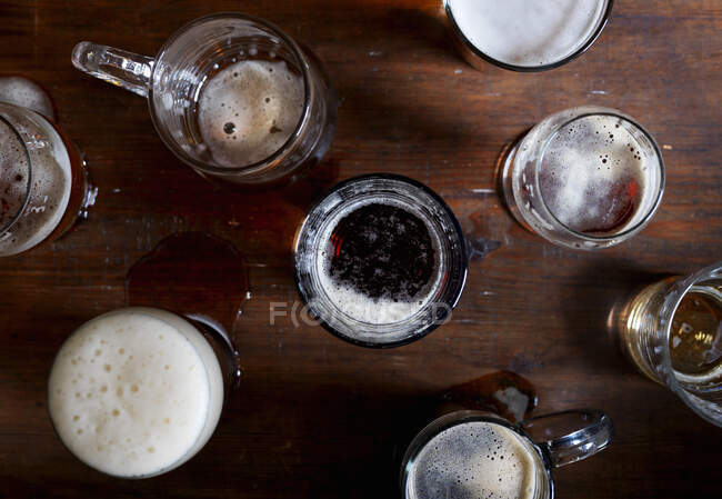Different beer in glasses on wooden table, top view — Stock Photo