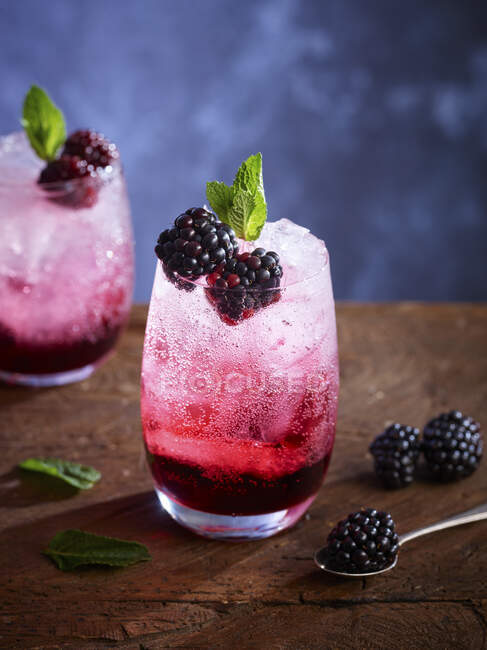 Bramble cocktails with crushed ice, blackberries and mint leaves in glasses — Stock Photo