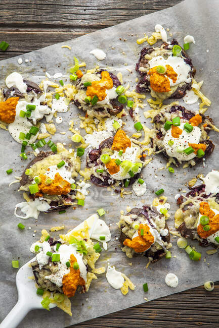 Squashed purple potatoes with cheese, sour cream and pesto — Stock Photo