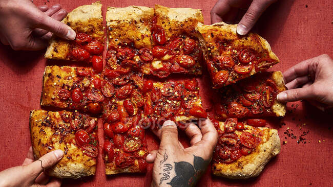 Pizza estilo romano coberto com tomates e flocos de pimenta vermelha esmagada com as mãos — Fotografia de Stock