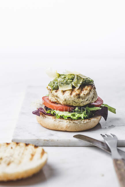Chicken burger with basil pesto and parmesan chesse — Stock Photo