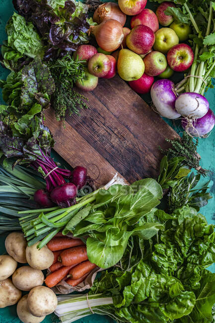 Legumes orgânicos e frutas com tábua de corte de madeira — Fotografia de Stock