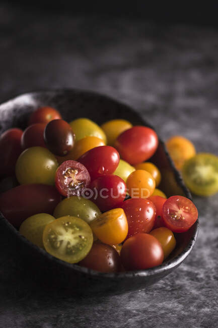 Tomates cereja em uma tigela preta — Fotografia de Stock