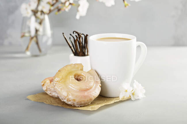 Donuts fritos de vainilla a la antigua con glaseado de brillo rosa y una taza de café - foto de stock
