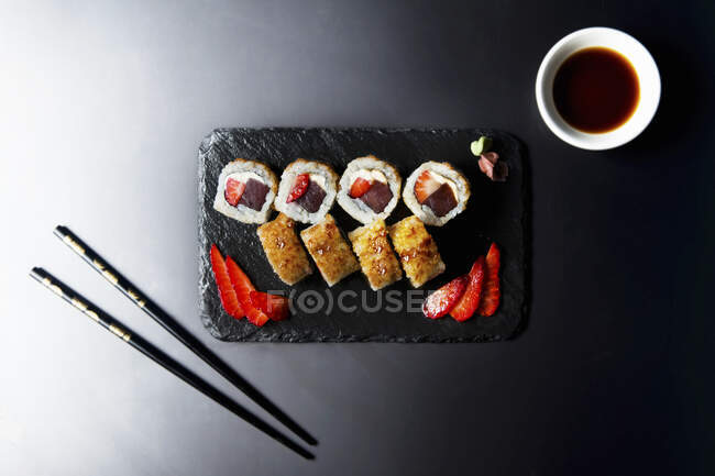 Rolos de sushi com atum, queijo de morango e creme, caramelo de cristal marrom em cima — Fotografia de Stock