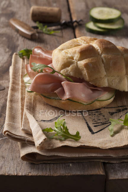 Bread roll with mortadella, cucumber and rocket salad — Stock Photo