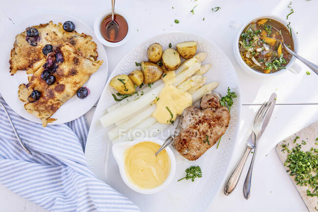 A menu with minestrone, pork with asparagus and blueberry pancakes — Stock Photo