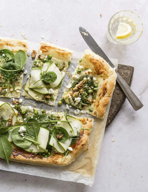 Una pizza cubierta con verduras verdes y nueces - foto de stock