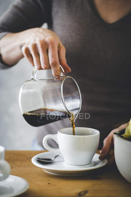 Nahaufnahme der Hand einer Frau, die Kaffee in eine Kaffeetasse gießt — Stockfoto