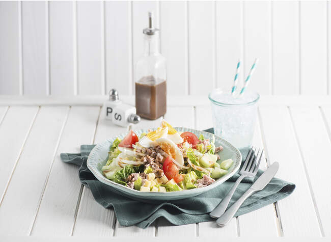 Nizza salad with tuna and egg, soda water with ice in glass — Stock Photo