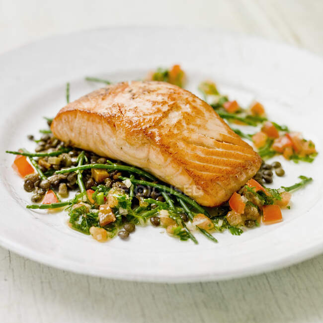 Salmon fillet on a bed of samphire, green lentils and tomatoes with green herbs vinaigrette — Stock Photo
