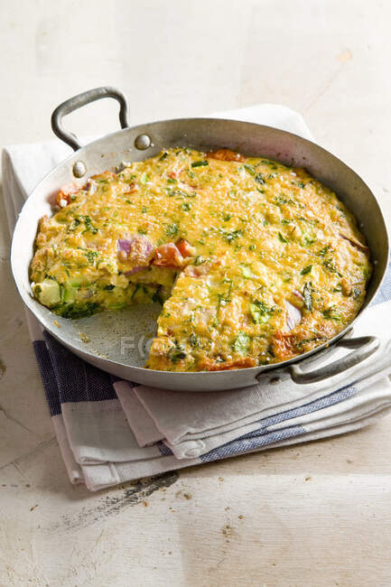 Frittata with zucchini, tomatoes and herbs in metal dish — Stock Photo