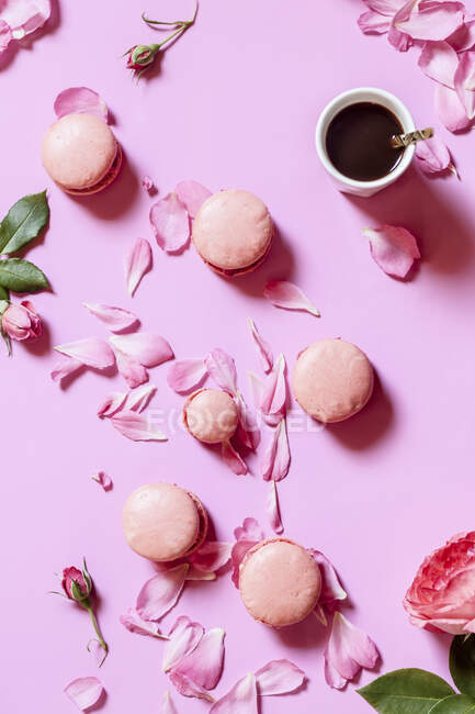 Macarrones rosados llenos de rosas y taza de café - foto de stock