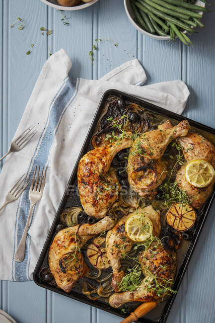 Chicken legs baked with onions, lemon, olives, garlic and thyme — Stock Photo