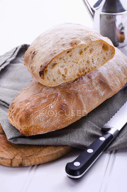 Cut Ciabatta with cloth on wooden board surface — Stock Photo