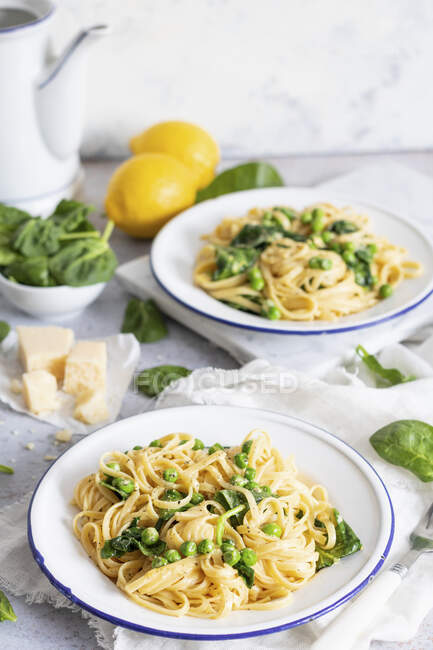 Pasta con spinaci, piselli e limoni sullo sfondo — Foto stock