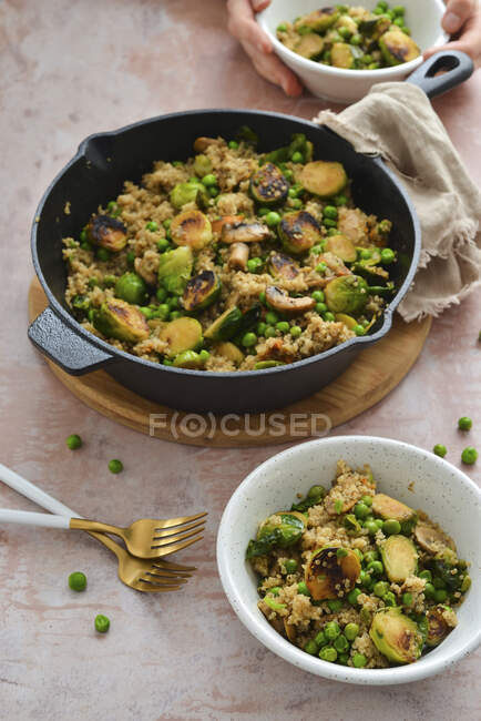 Quinoa con cavoletti di Bruxelles caramellati piselli verdi e patate dolci in padella — Foto stock