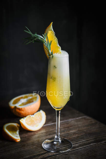 Cóctel de alcohol con cuña naranja y romero en copa de champán - foto de stock