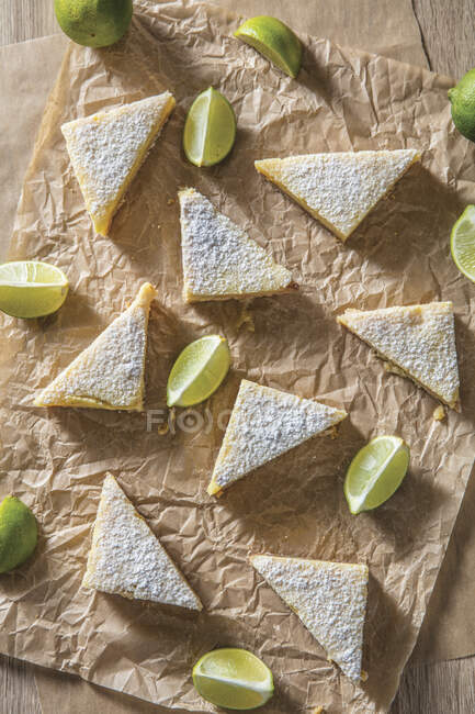 Key lime bars triangles with lime slices on butcher paper — Stock Photo