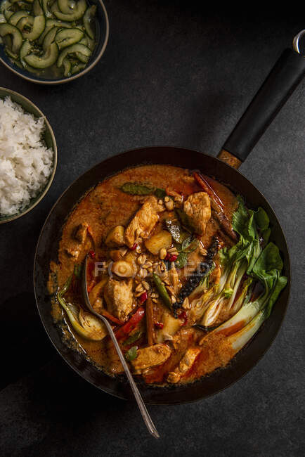 Thai Massaman pollo al curry con arachidi, patate novelle, peperoni, pakchoi, thai lime cetriolo gusto e riso gelsomino — Foto stock