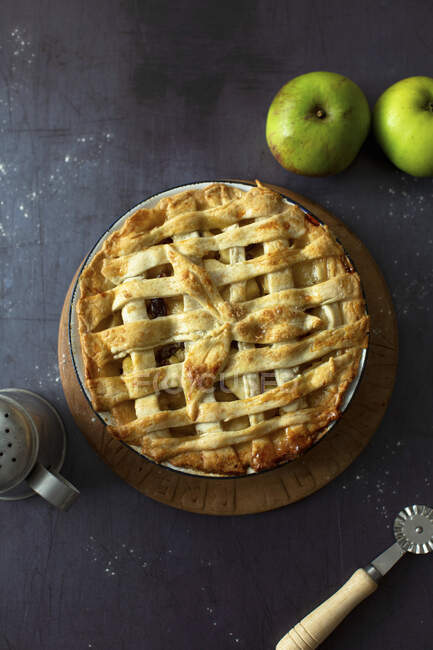 Яблочный пирог с круглым ножом и свежими яблоками — стоковое фото