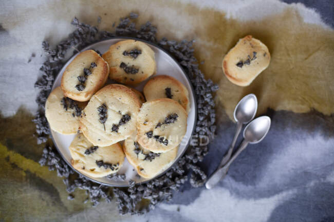 Biscuits à la lavande avec des fleurs sur une assiette avec deux cuillères — Photo de stock