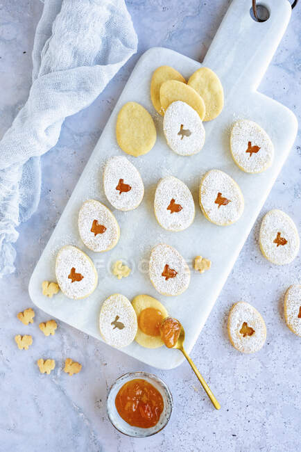 Easter eggs cookies with apricot jam on marble cutting board — Stock Photo