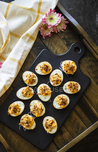Ovos recheados a bordo com pano e flores à mesa de madeira — Fotografia de Stock