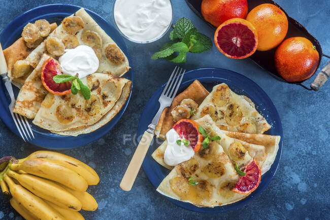 Bananen-Crêpes mit Besteck auf blauem Tisch — Stockfoto