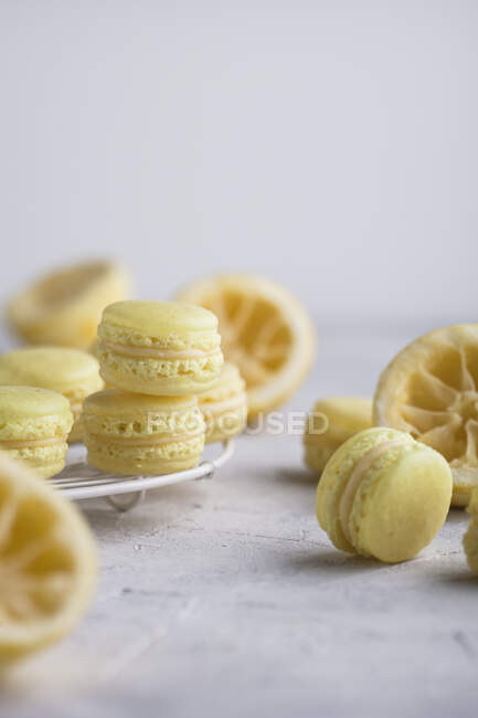Mini lemon macarons with squeezed lemons on table — Stock Photo