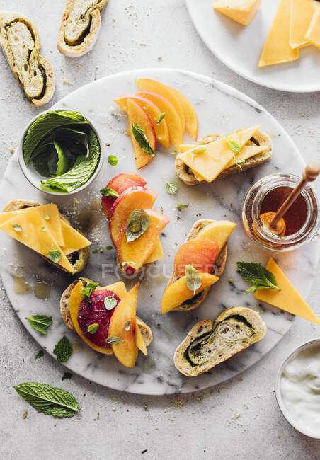 Cheese appetizers with peaches, mint and honey — Stock Photo