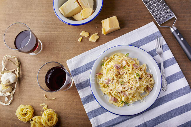 Homemade pasta Carbonara with parmesan cheese and glasses of red wine — Stock Photo