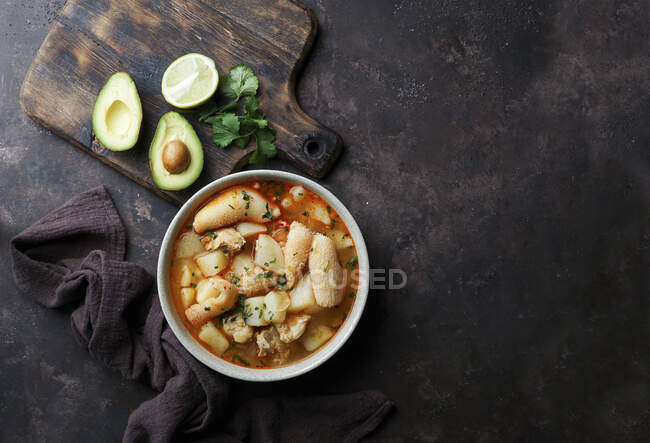 Bowl of tasty chicken soup with lemon and garlic on black background — Stock Photo