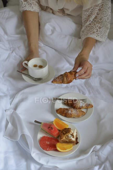 Petit déjeuner au lit croissants fruits et café — Photo de stock